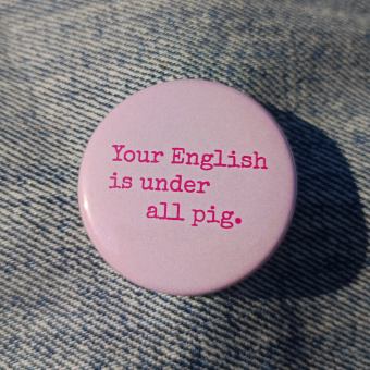 Ansteckbutton Your English is under all pig auf Jeans